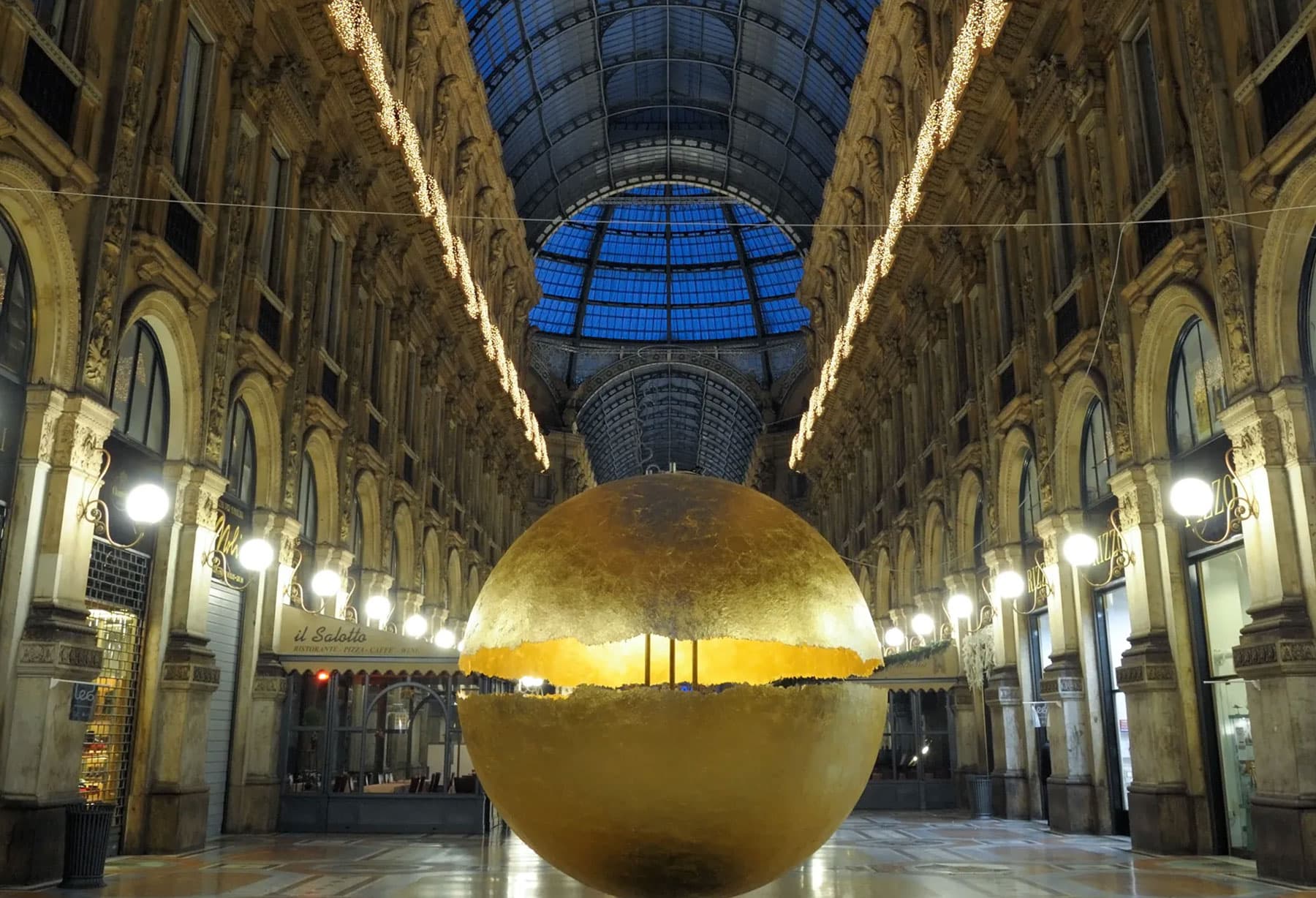 <p>Die Installation „PostKrisi“ in der Galerie Vittorio Emanuele in Mailand besteht aus einer großen, auf dem Boden aufliegenden, leuchtenden und imposanten Kugel, die in einer Anordnung vollständig mit Blattgold bedeckt ist, die einen Wert der Vergangenheit mit der heutigen Technologie verbindet.</p>
